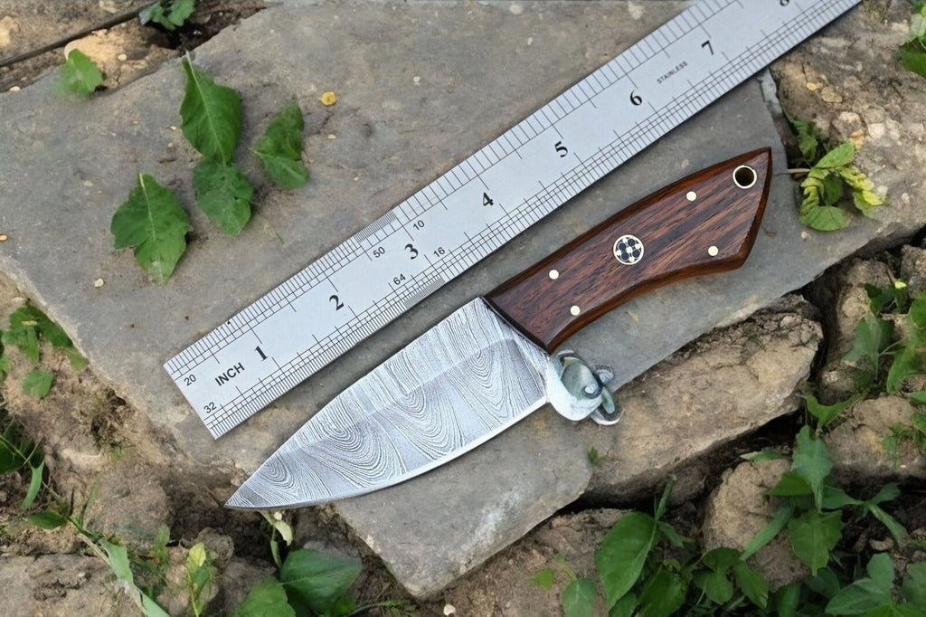 Handmade Damascus hunting knife with a polished rosewood handle and intricate blade pattern, displayed on a neutral background.