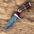 Handmade Damascus hunting knife with a polished blade and antler horn handle, displayed on a wooden surface.