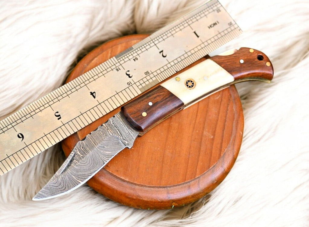 Handmade Damascus Steel Pocket Knife with rosewood and bone handle, featuring intricate blade pattern and craftsmanship.