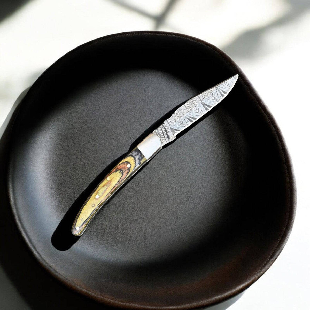 Handmade Damascus pocket knife with an exotic wood handle, featuring a detailed Damascus steel blade.