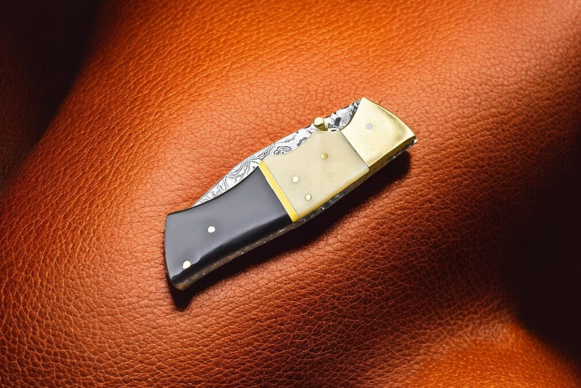 Handmade Damascus pocket knife with bone and buffalo horn handle, featuring a sharp stainless steel blade.