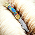 Custom handmade Damascus pocket knife with multi-color wood handle, featuring a detailed Damascus steel blade and vibrant wood scales.