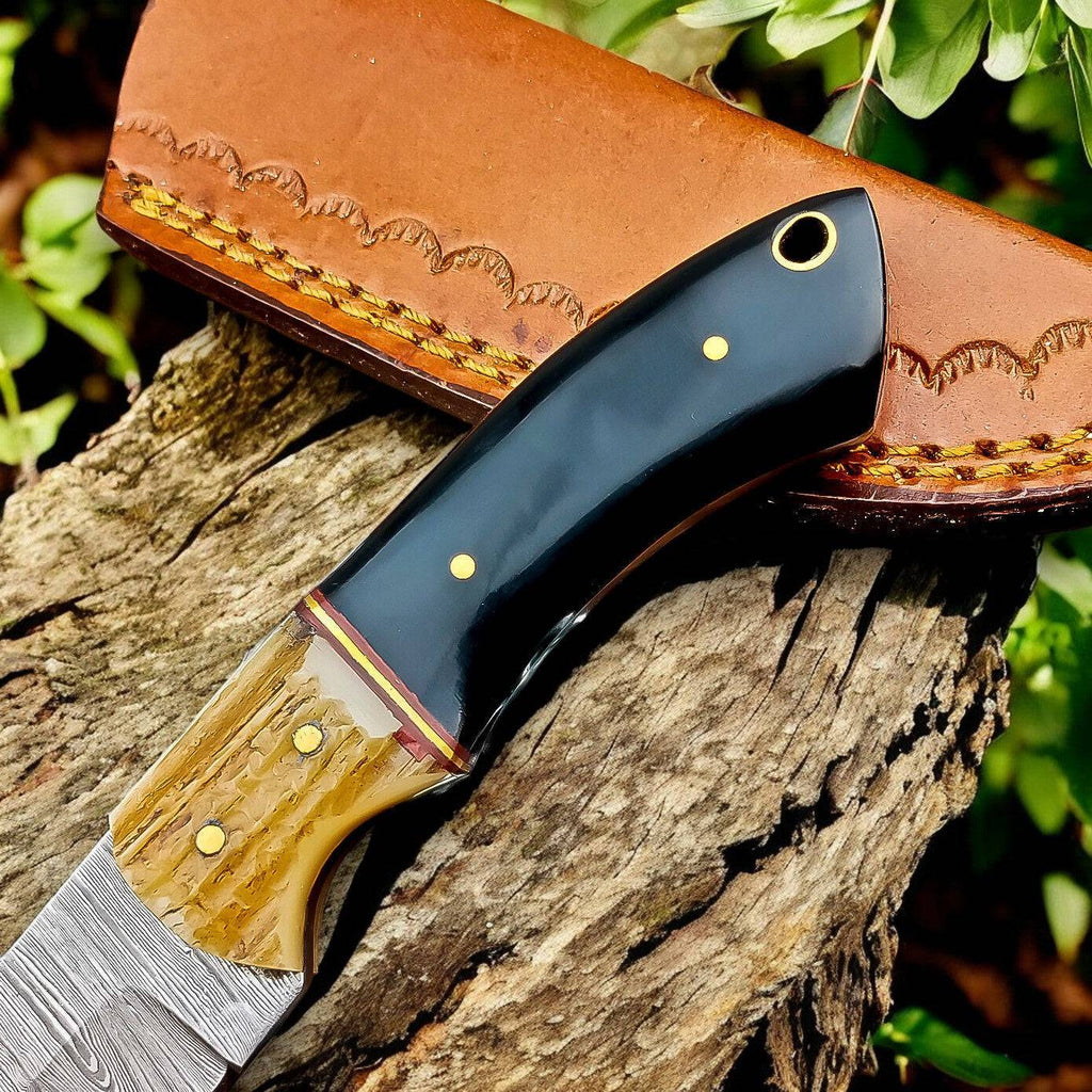 Handmade Damascus hunting knife with buffalo horn handle and antler accents, showcasing intricate blade pattern and craftsmanship.