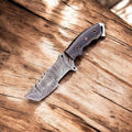 Handmade Damascus Tanto hunting knife with Micarta handle and intricate blade pattern, displayed on a plain background.