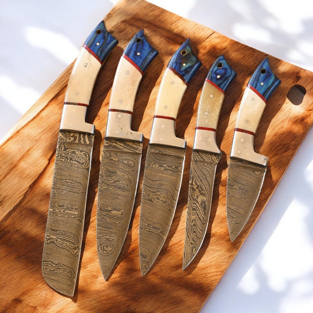Handmade Damascus kitchen knives set with exotic wood handles and bone accents, displayed on a wooden surface.