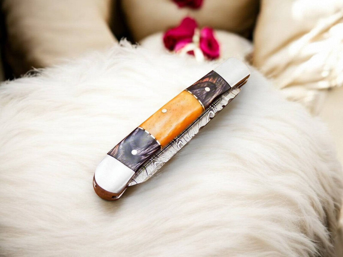 Handmade Damascus pocket knife with exotic wood handle and bone accents, showcasing intricate blade craftsmanship.