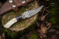 Handmade Damascus skinning knife with epoxy resin handle and bone accents, featuring a sharp stainless steel blade.
