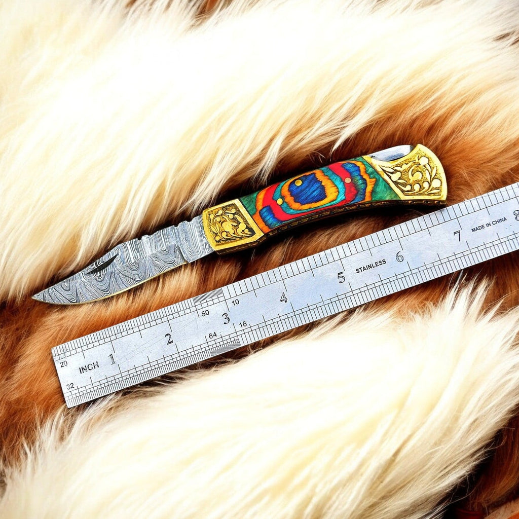 Custom handmade Damascus pocket knife with multi-color wood handle, featuring intricate blade design and polished wooden grip.