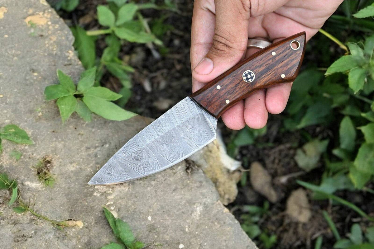 Handmade Damascus hunting knife with a polished rosewood handle and intricate blade pattern, displayed on a neutral background.