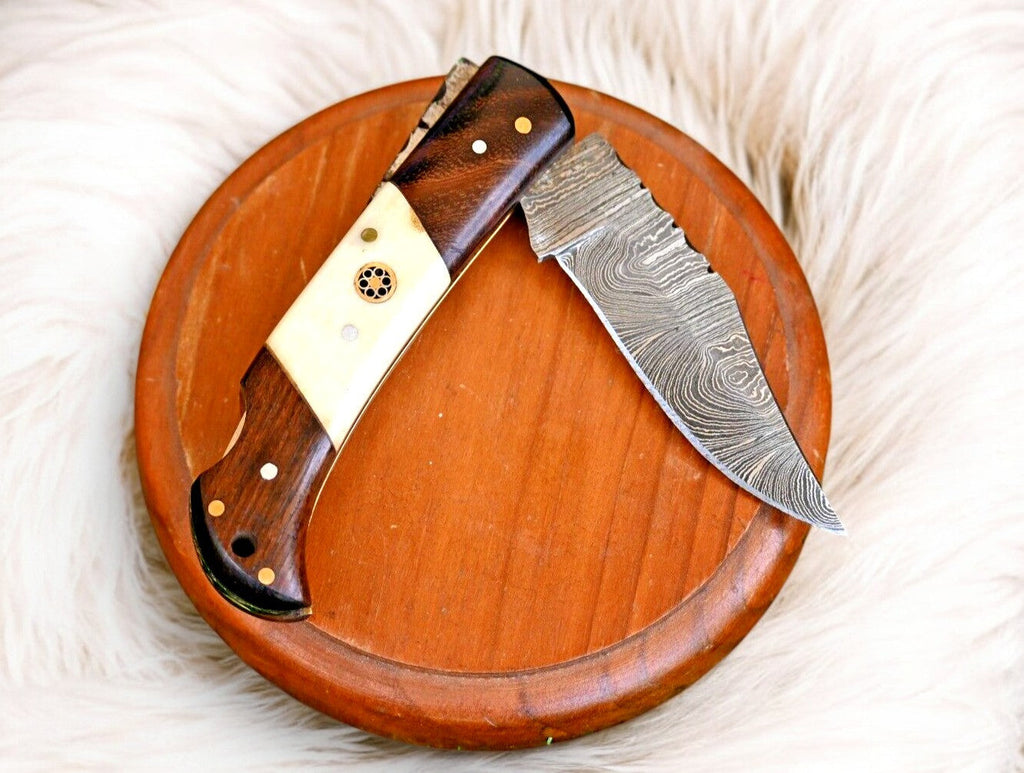Handmade Damascus steel pocket knife with rosewood handle and bone accents, showcasing intricate blade details and craftsmanship.