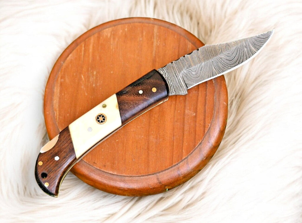 Handmade Damascus Steel pocket knife with rosewood handle and bone accents, showcasing intricate steel pattern and craftsmanship.