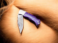 Custom handmade Damascus pocket knife with a vibrant colored bone handle, featuring intricate damascus steel blade.