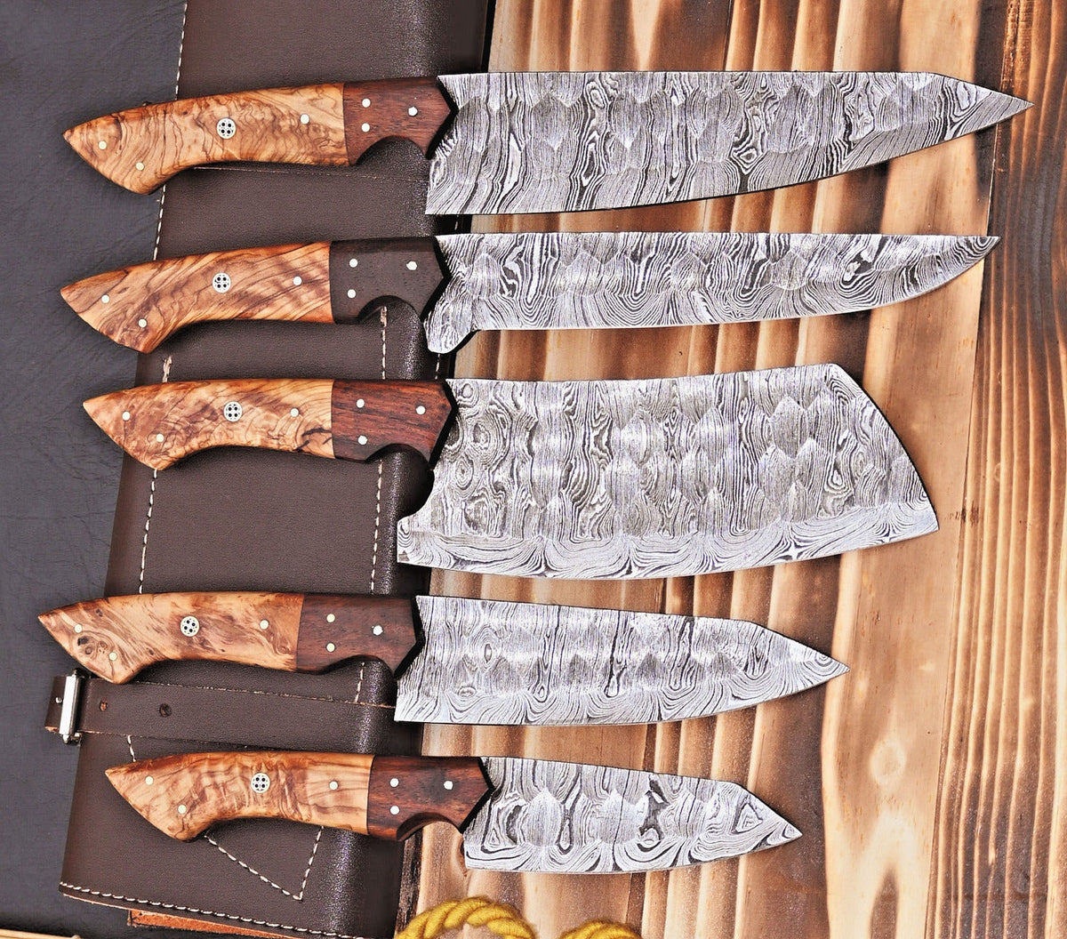 Premium Damascus Kitchen Knife Set by Knives Gear Garage featuring handcrafted blades with elegant patterns and wooden handles.
