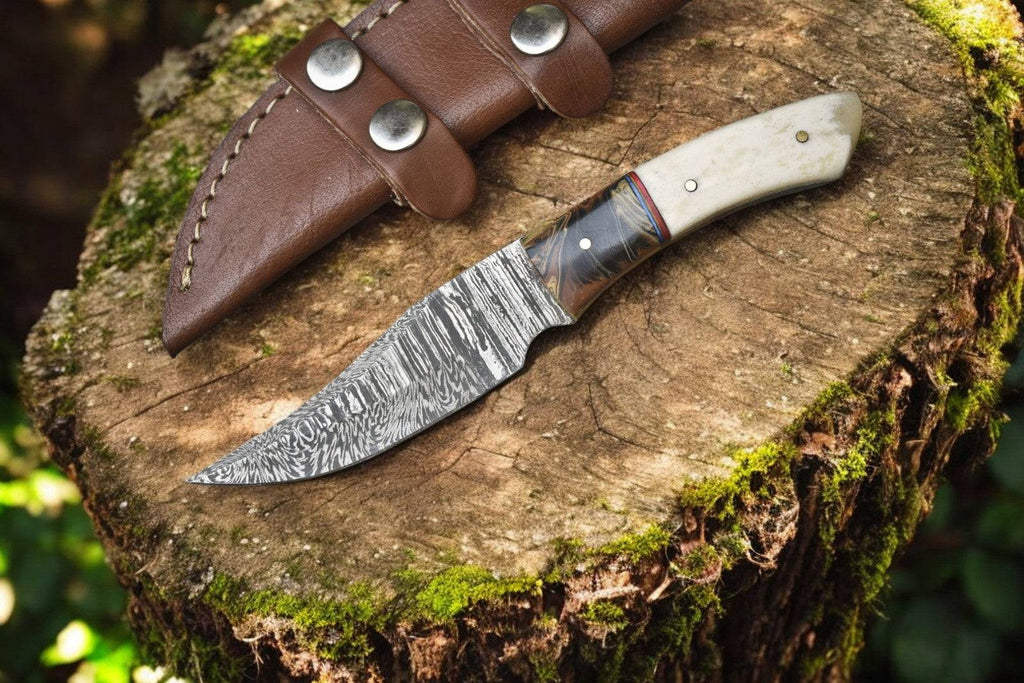 Handmade Damascus skinning knife with epoxy resin handle and bone accents, showcasing intricate Damascus steel blade.