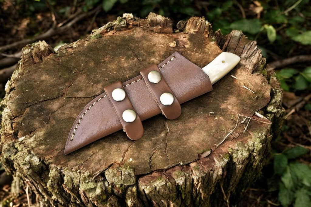 Handmade Damascus skinning knife with epoxy resin handle and bone accents, featuring a sharp, curved blade for precise skinning tasks.