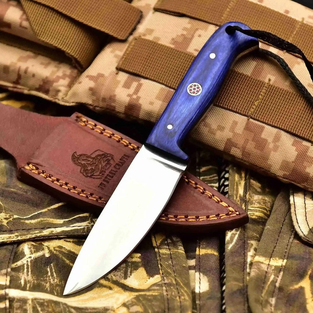 JW SteelCrafts Prairie Blade survival skinning knife with carbon steel blade and multiple handle colors on camouflage background.