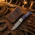 Western Cowboy Damascus folding pocket knife with a purple Pakka wood handle and stainless steel blade by SHAM KNIVES.